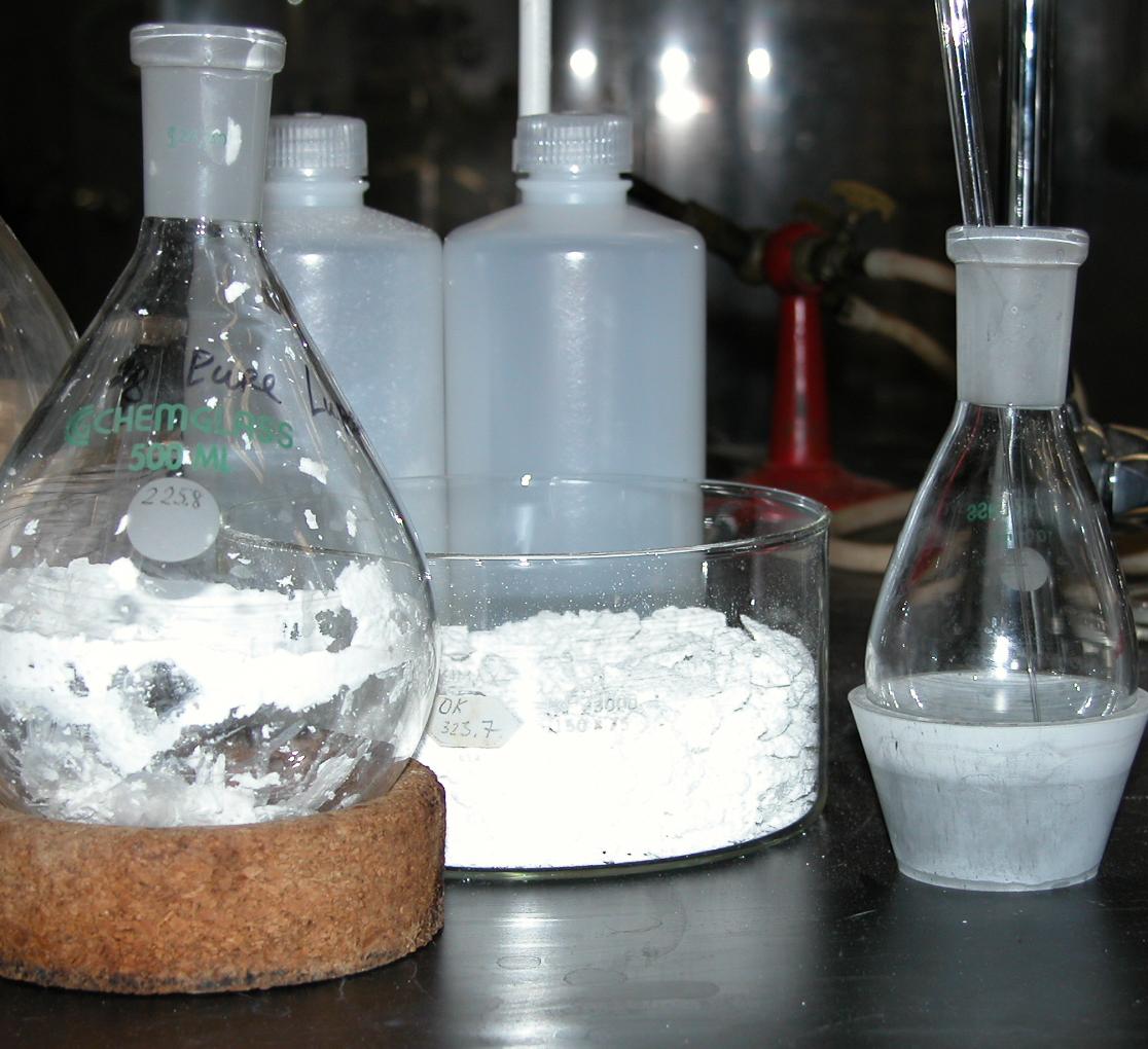 Chemistry vials with white powder sit on a bench top.